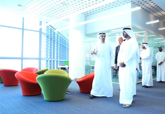 Khalifa University directors and leadership walk through the modern campus in traditional Arabic clothes. 